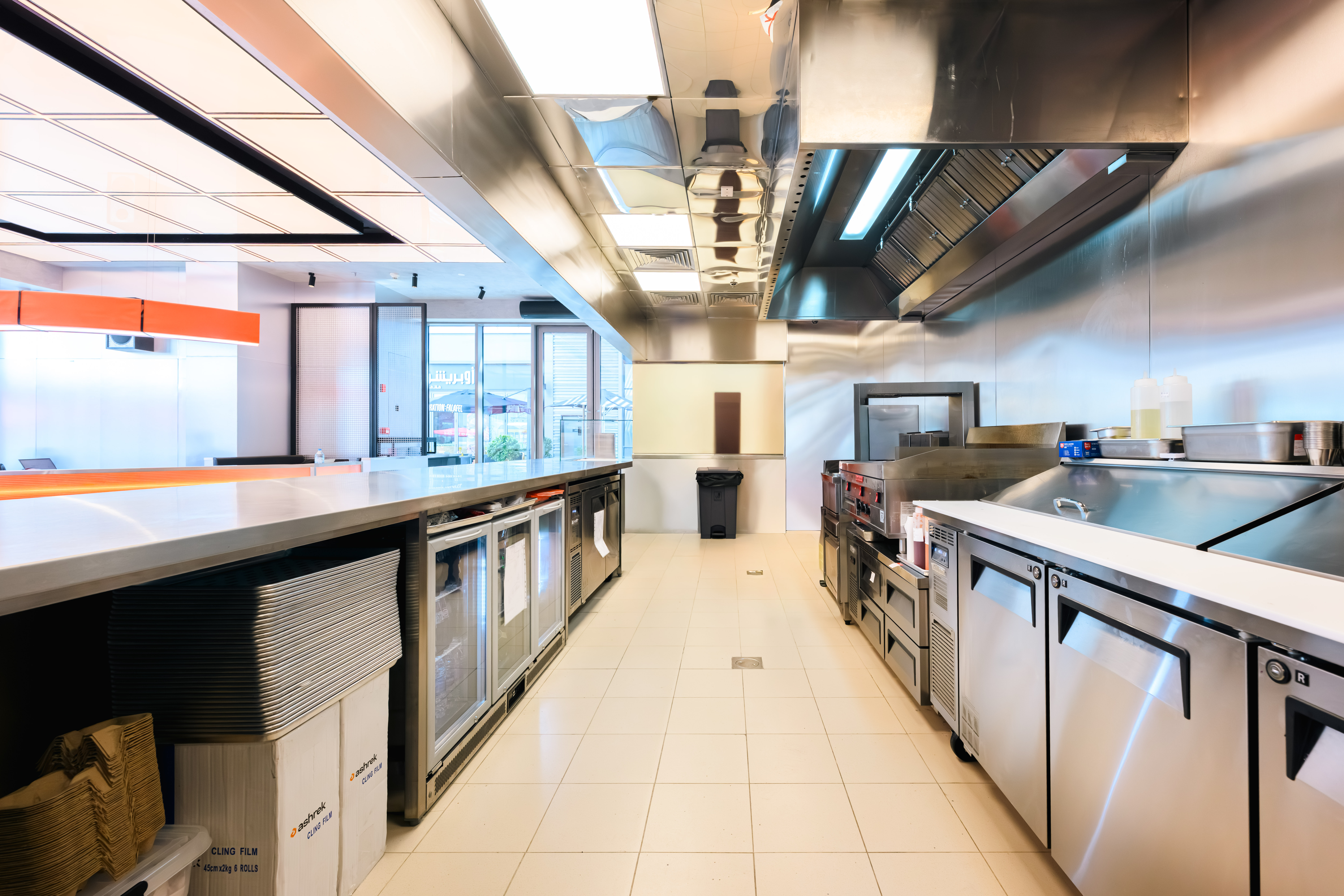 Alien Burger JBR kitchen line by Cleresdyne showing the cooking line, hood canopy, undercounter refrigeration, and service pass