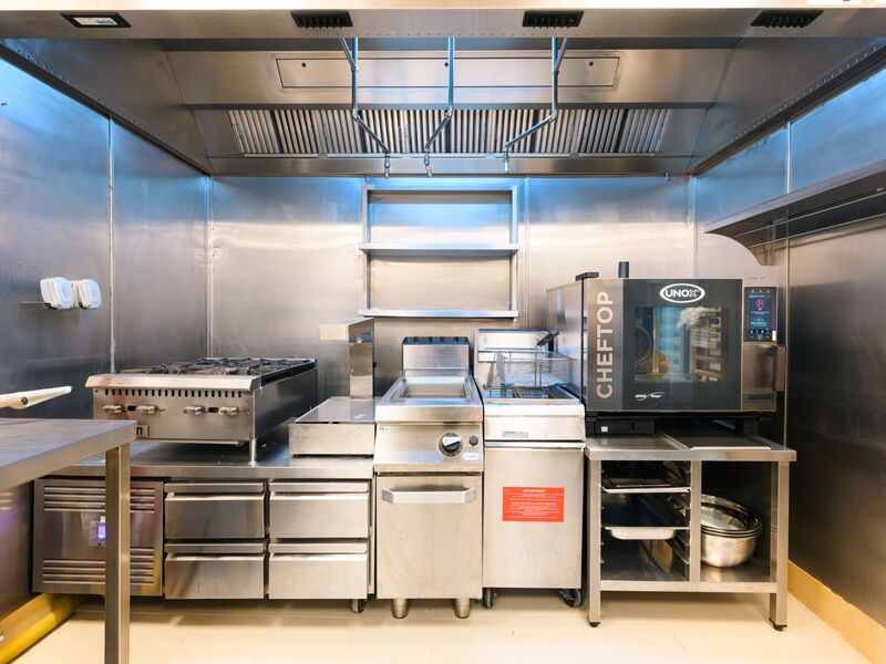 Alien Burger JBR kitchen retrofit by Cleresdyne, featuring Unox combi oven, gas range, fryers, and full stainless steel wall cladding